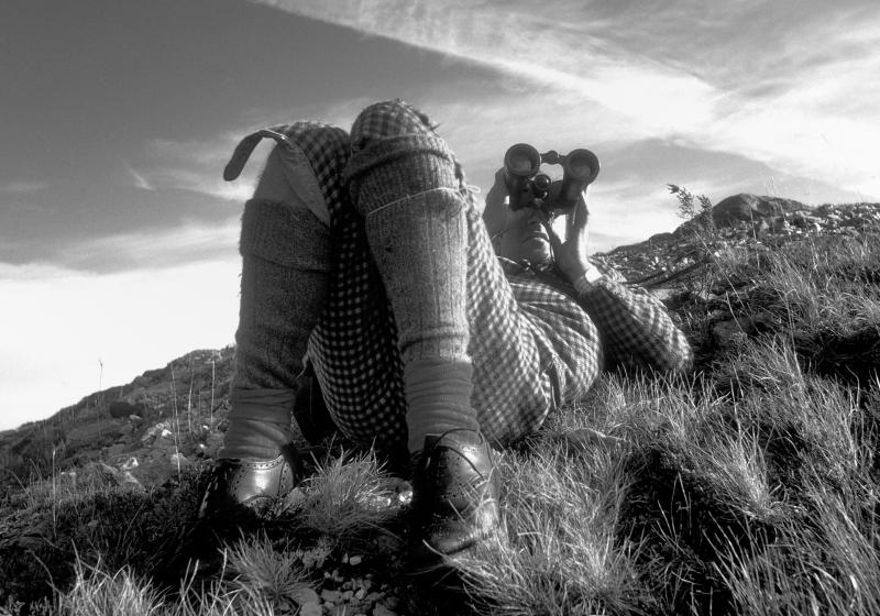 Coulin Estate.Deer Stalker spying through binoculars. Traditional tweed clothing. Black and white